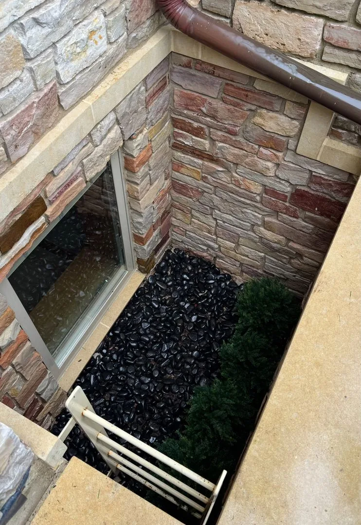 Clean stone egress window well with river rock in Wheeling IL after Perfect Touch window well cleaning