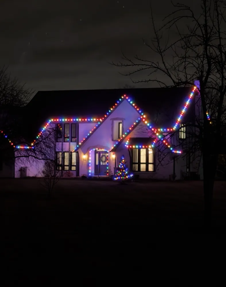 Multicolor C9 Christmas roofline lights on a Tudor home at night in the North Shore - Perfect Touch