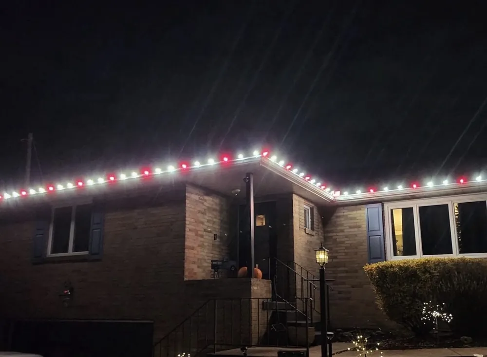 Red and white Christmas roofline lights on a brick ranch home in Wheeling, IL - Perfect Touch