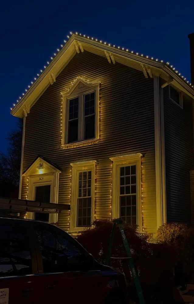 Warm white Christmas lights outlining windows and trim on a home at night in the North Shore - Perfect Touch